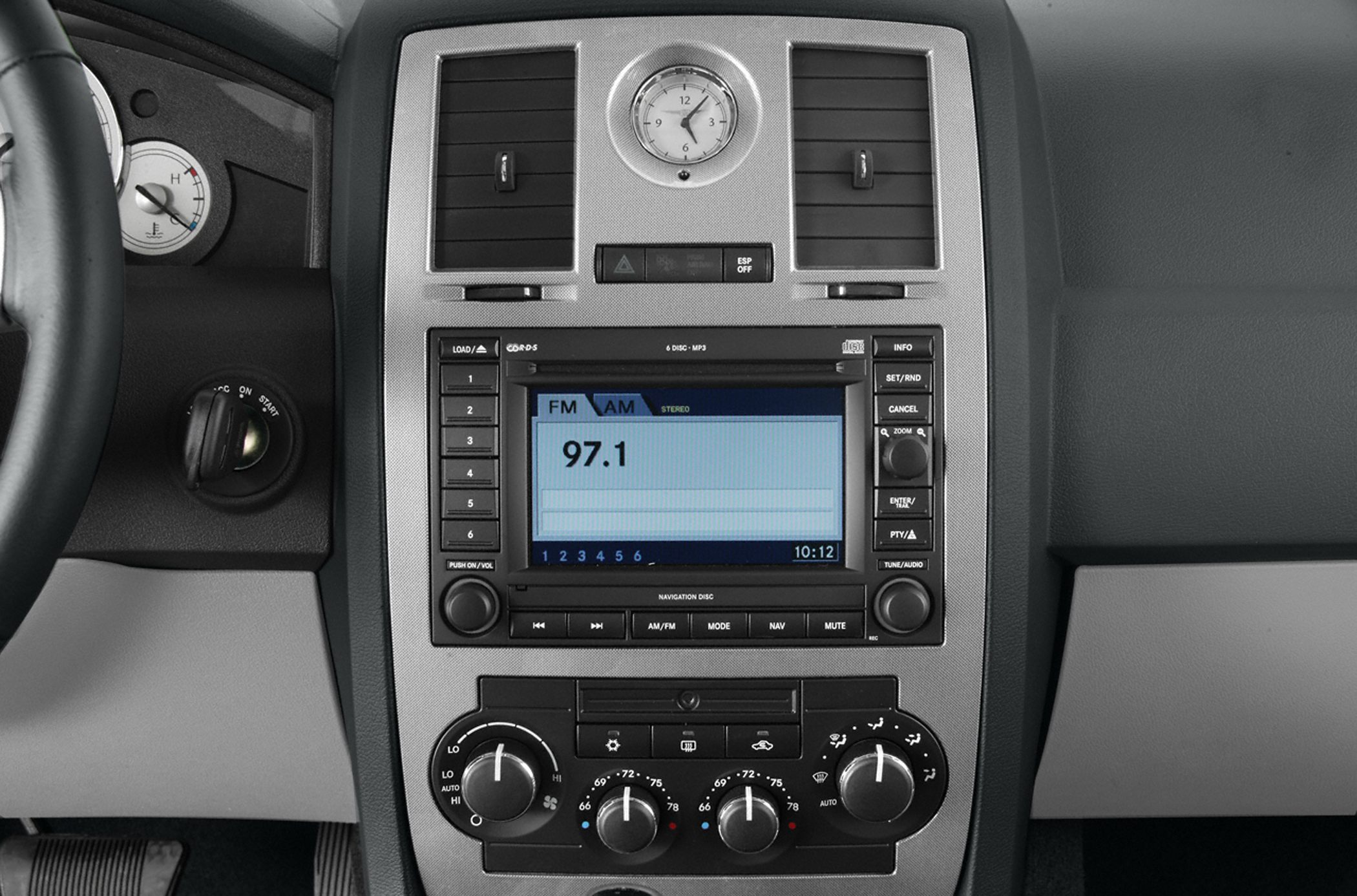 Analog clock, dual air vents, car radio, and climate controls on dashboard