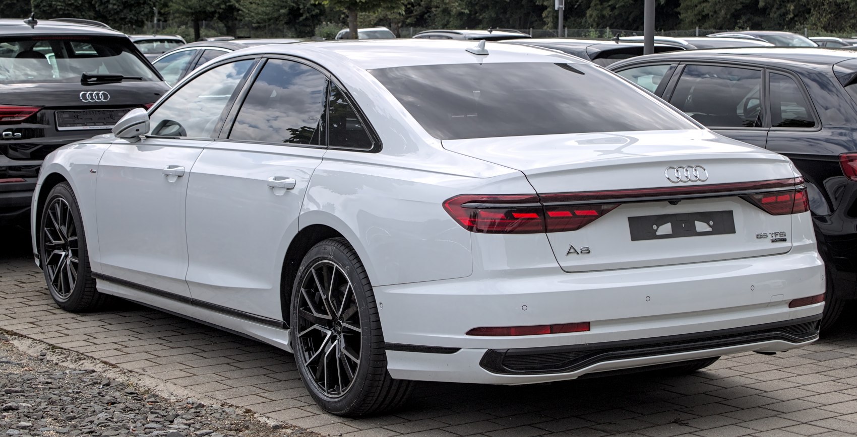 White sedan rear view with modern LED tail lights and multi-spoke black alloy wheels