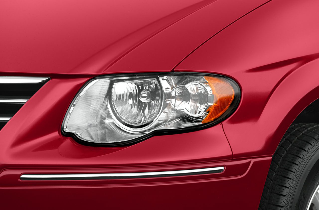 Close-up of front headlight and grille on red vehicle body