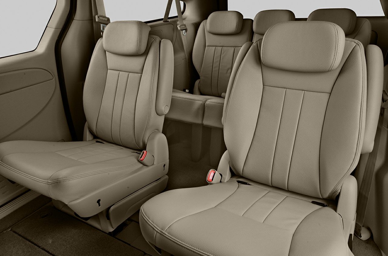 Spacious beige leather captain chairs and bench seating in vehicle interior.