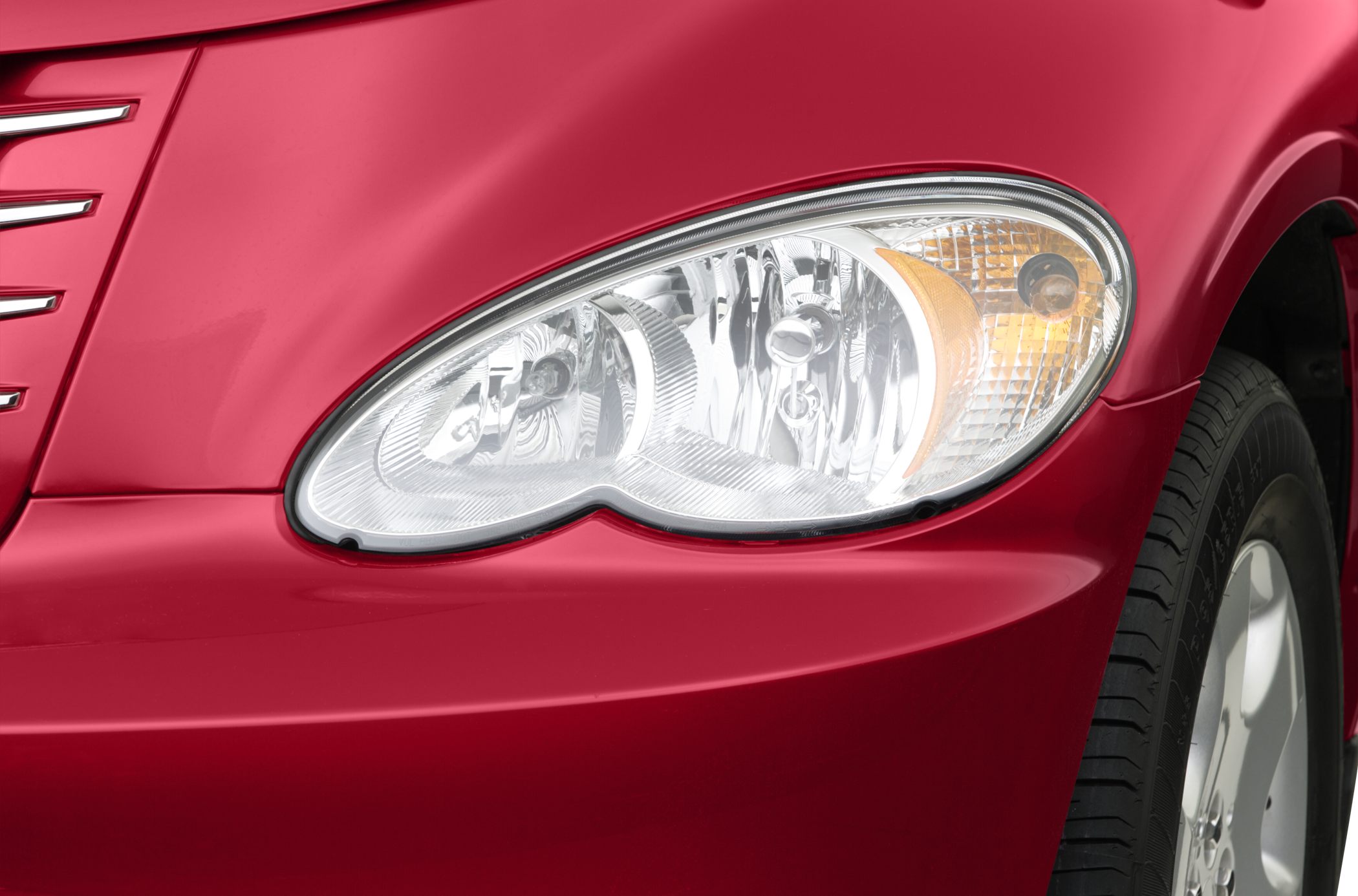 Close-up of car headlight and front fender with wheel visible