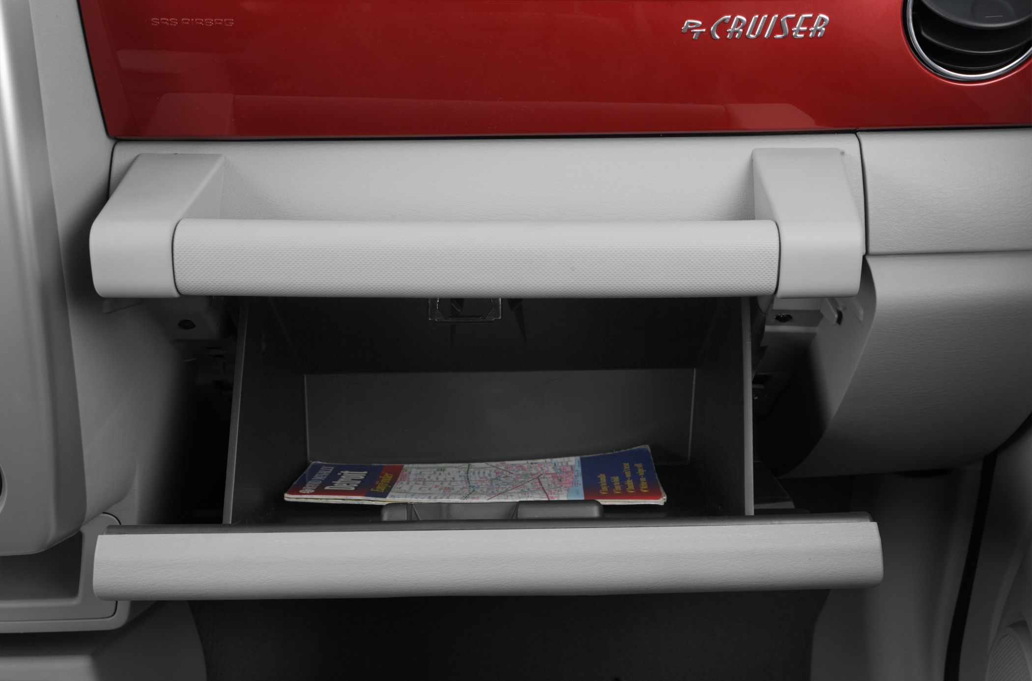 Open glove compartment with PT Cruiser logo on red dashboard panel
