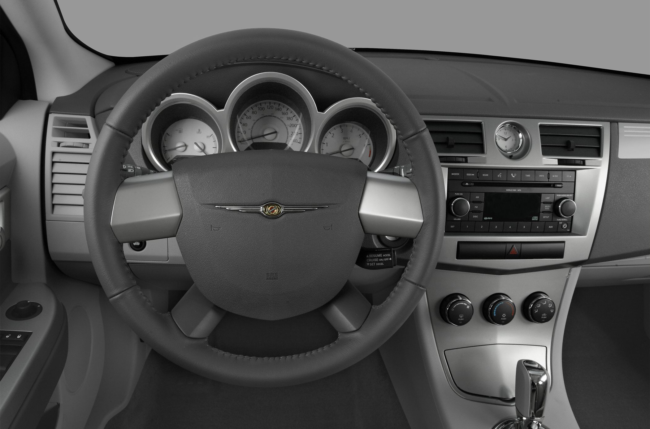 Steering wheel and dashboard with gauges, clock, and control knobs.