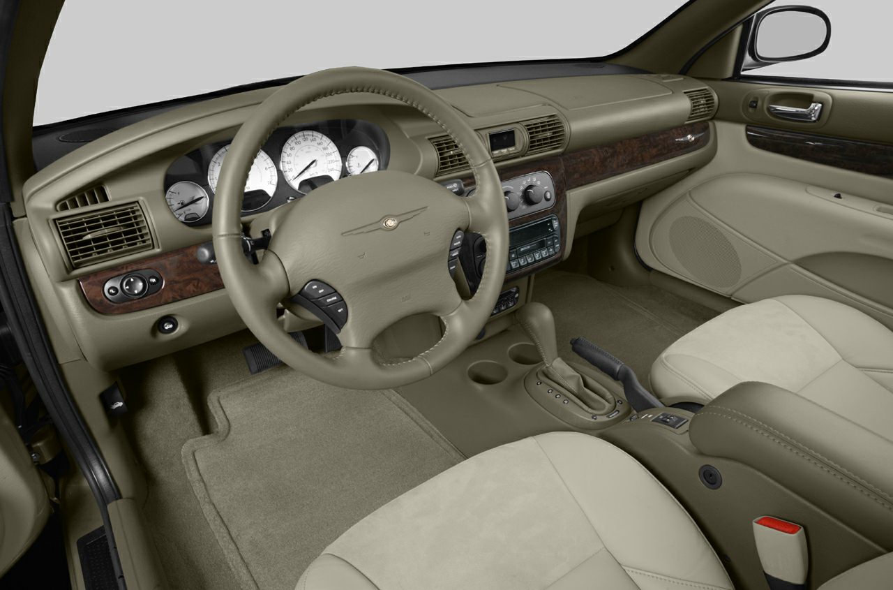 Car interior with dashboard, steering wheel, beige upholstery, and wood trim
