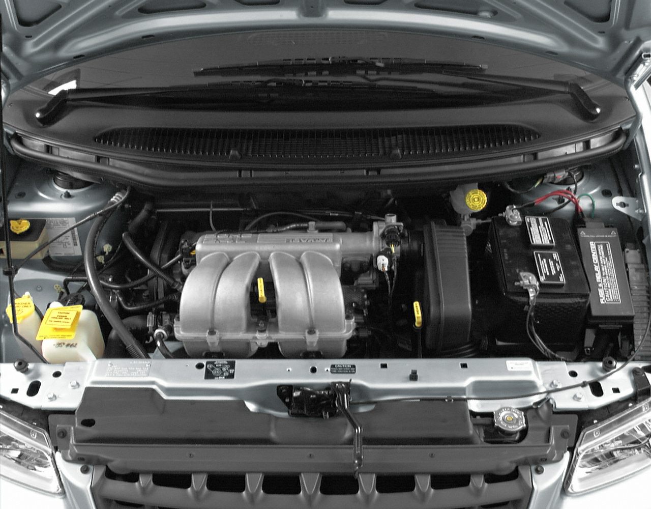 Engine bay showing intake manifold, battery, and fluid reservoirs under open hood.