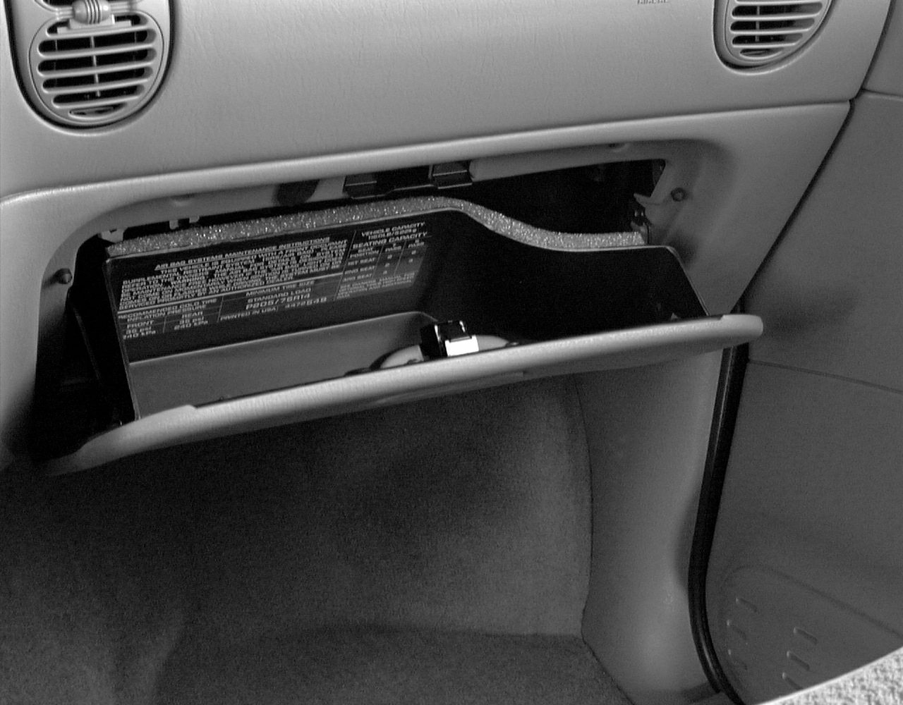 Open glove compartment with information label inside dashboard