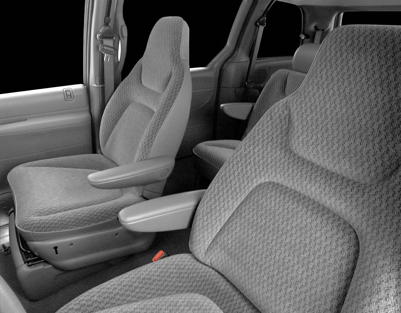 Close-up of fabric vehicle seats with armrests in front and rear seating area