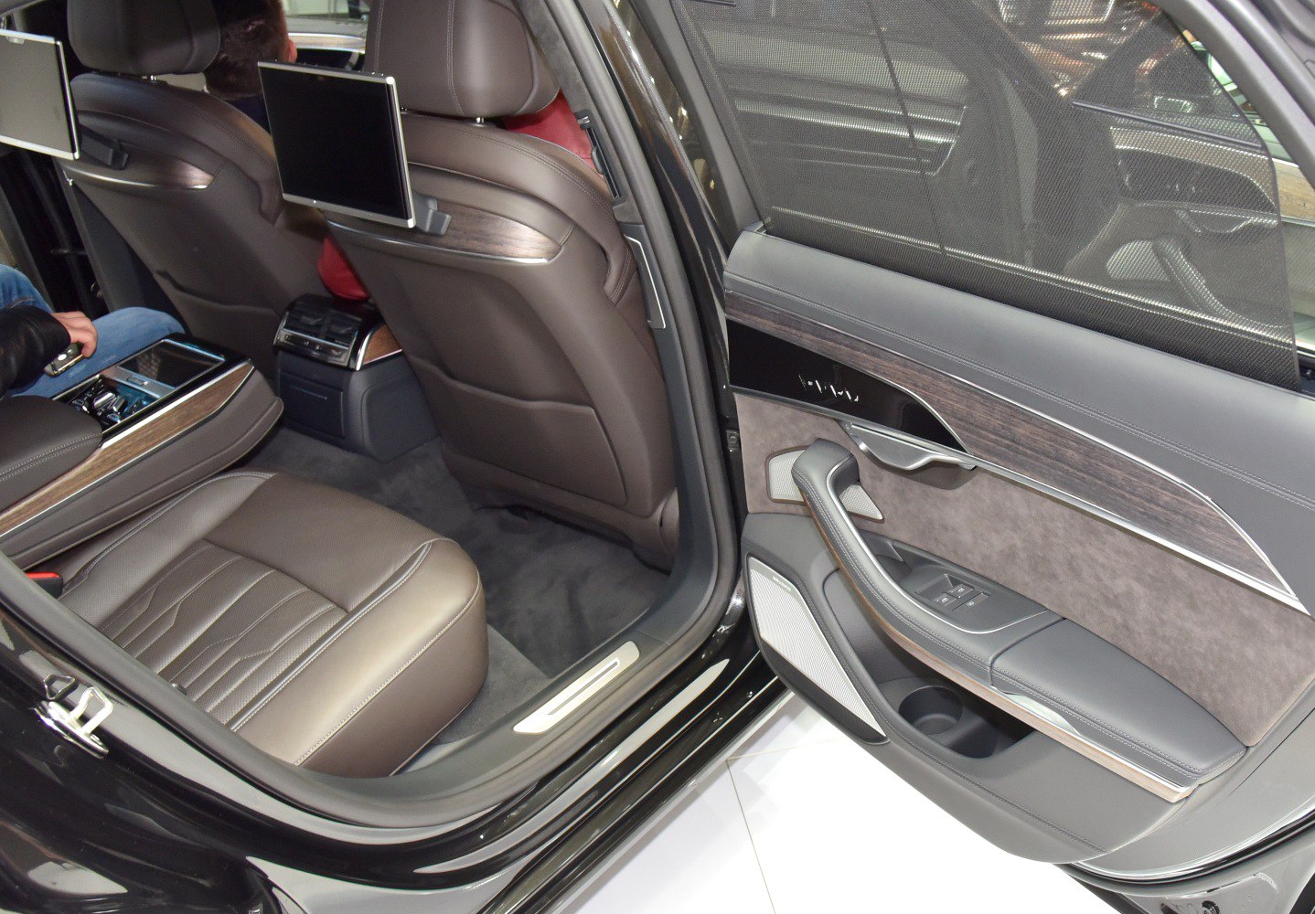 Rear seat interior with leather upholstery, wood trim, and rear entertainment screens.