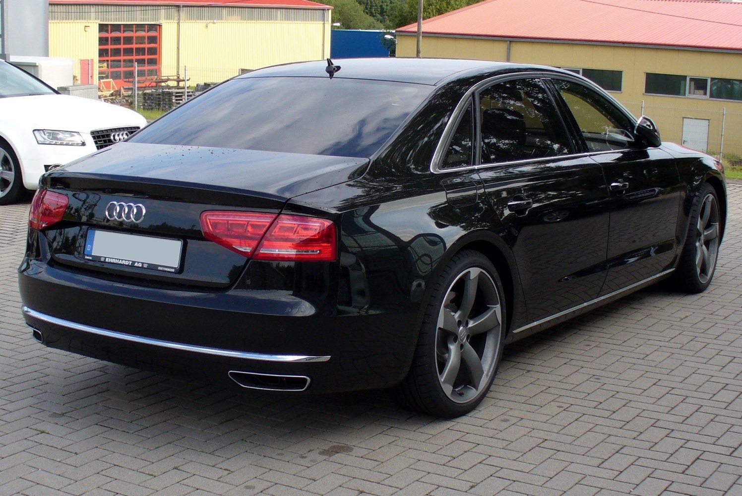 Rear and side profile of a black luxury sedan with tinted windows and alloy wheels.