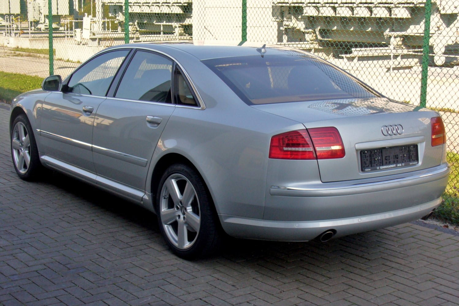 Silver luxury sedan rear-side profile with alloy wheels and distinct taillights