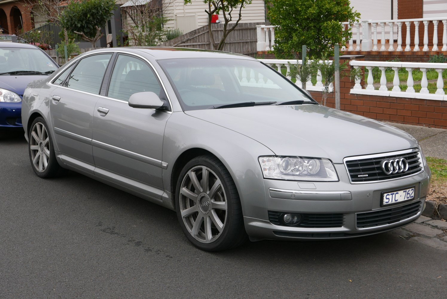 Silver sedan with dual headlights and large alloy wheels in urban street parking