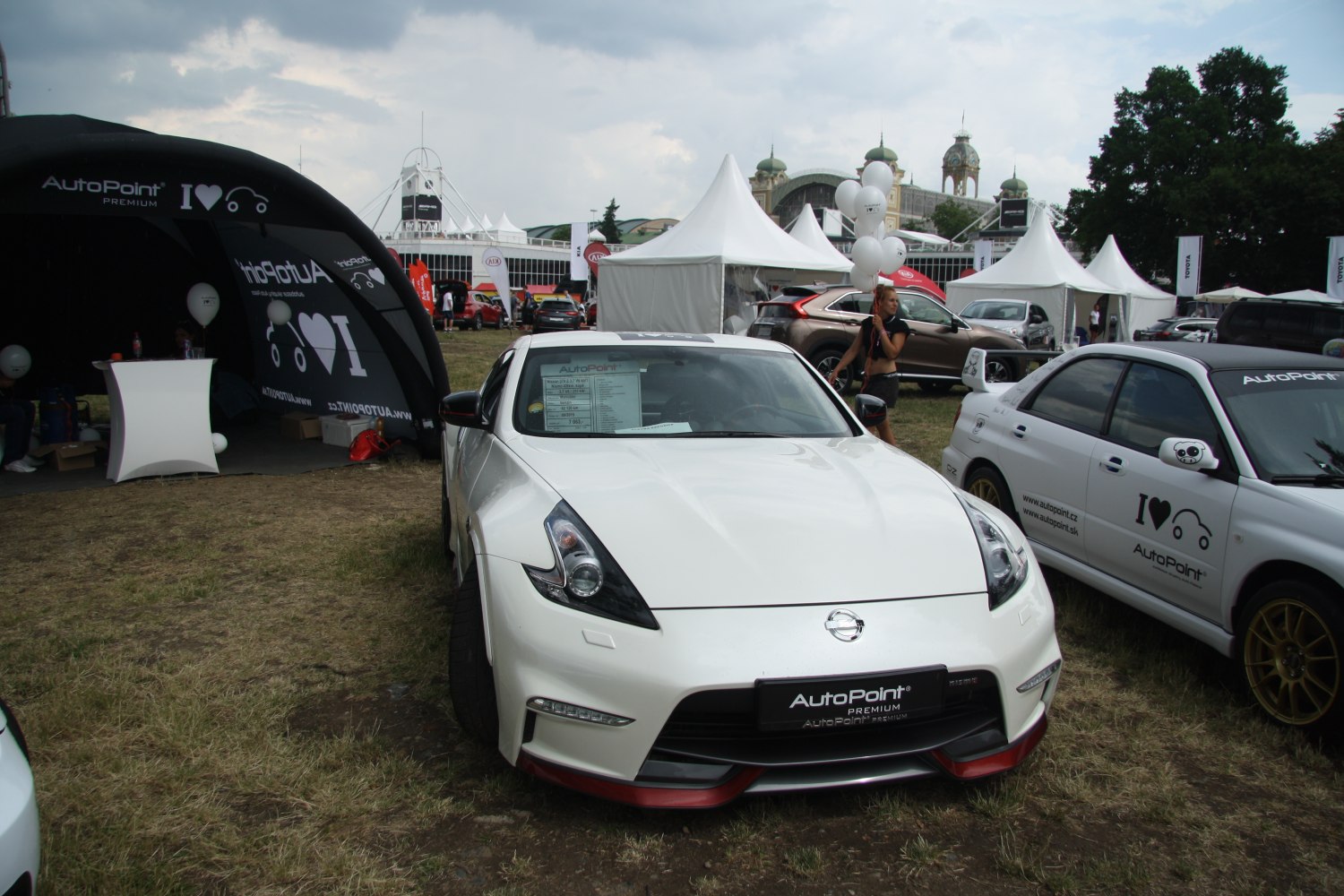 White Nissan 370Z coupe with an aerodynamic front bumper at an auto event.