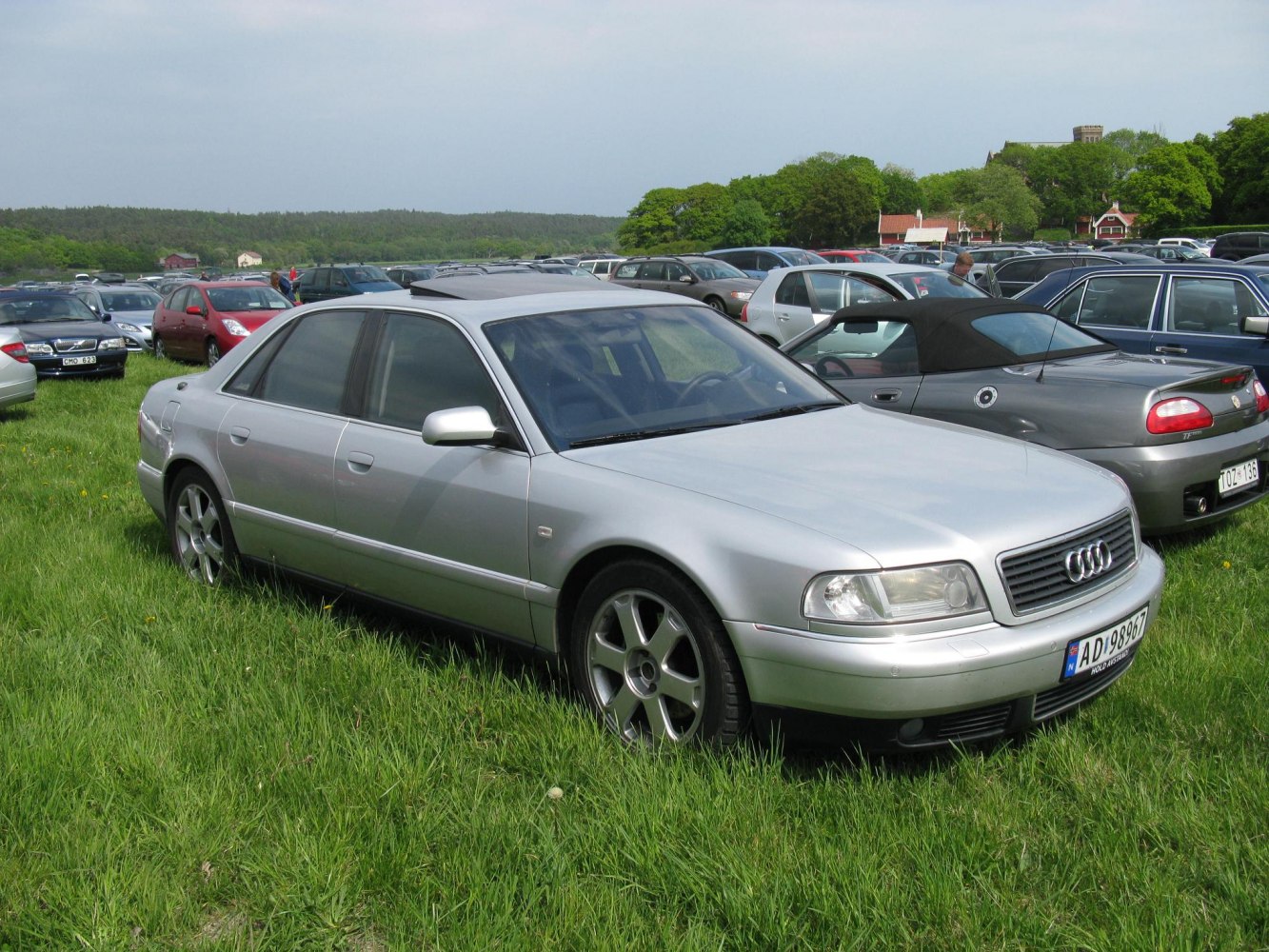 Silver sedan with alloy wheels and sunroof parked on grass.