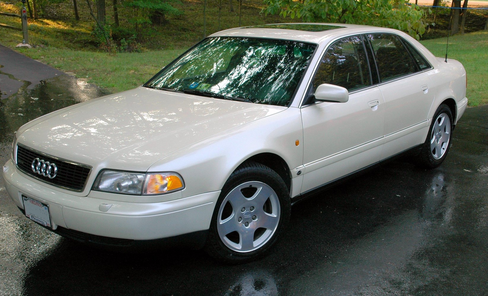 White classic luxury sedan with alloy wheels, side and front view.