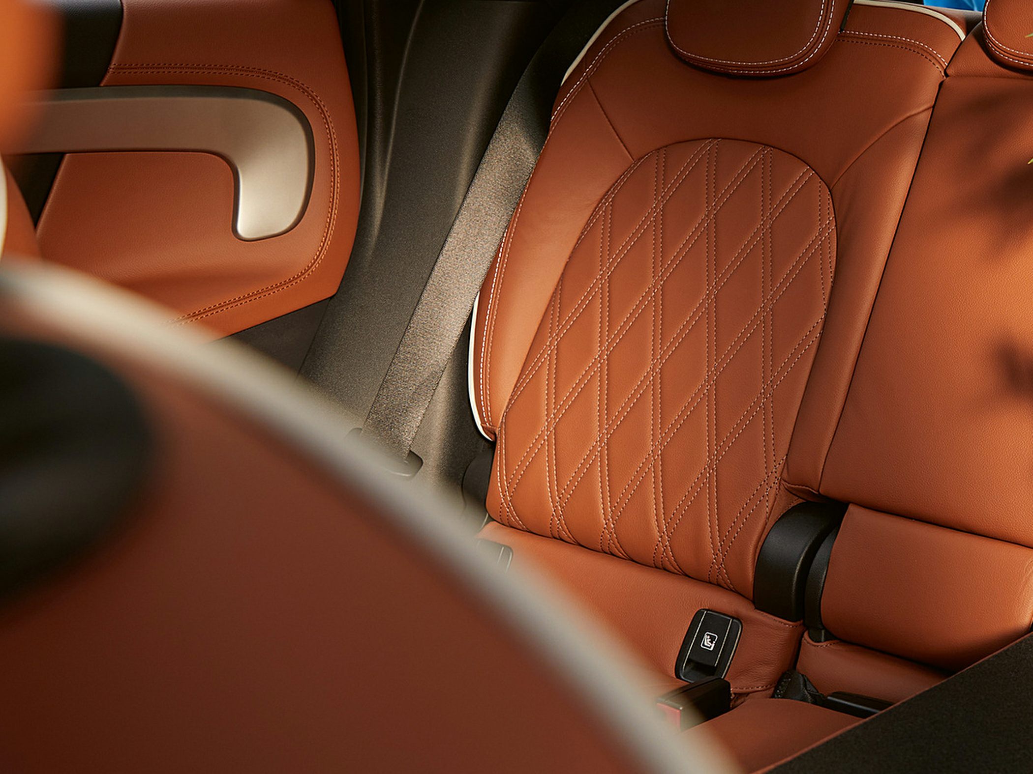 Luxurious tan leather seat with diamond stitching and seatbelt