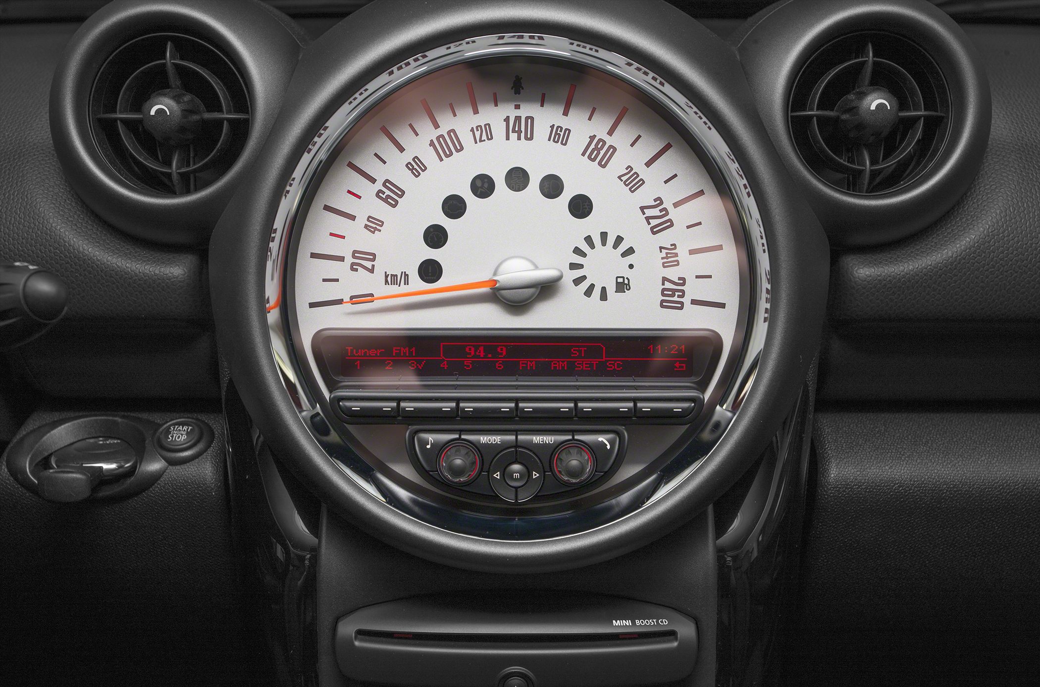 Dashboard speedometer and infotainment controls with circular air vents