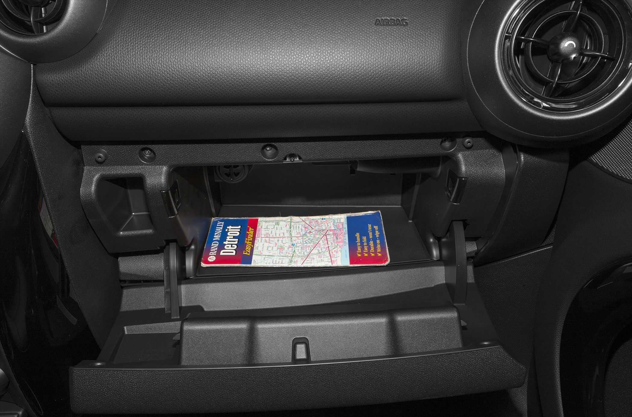 Open glove compartment with a Detroit city map inside