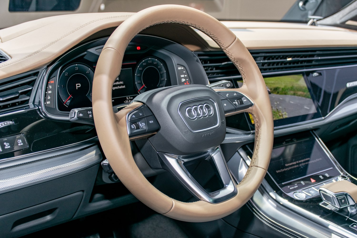 Luxury beige leather steering wheel with modern multi-function controls and digital dashboard