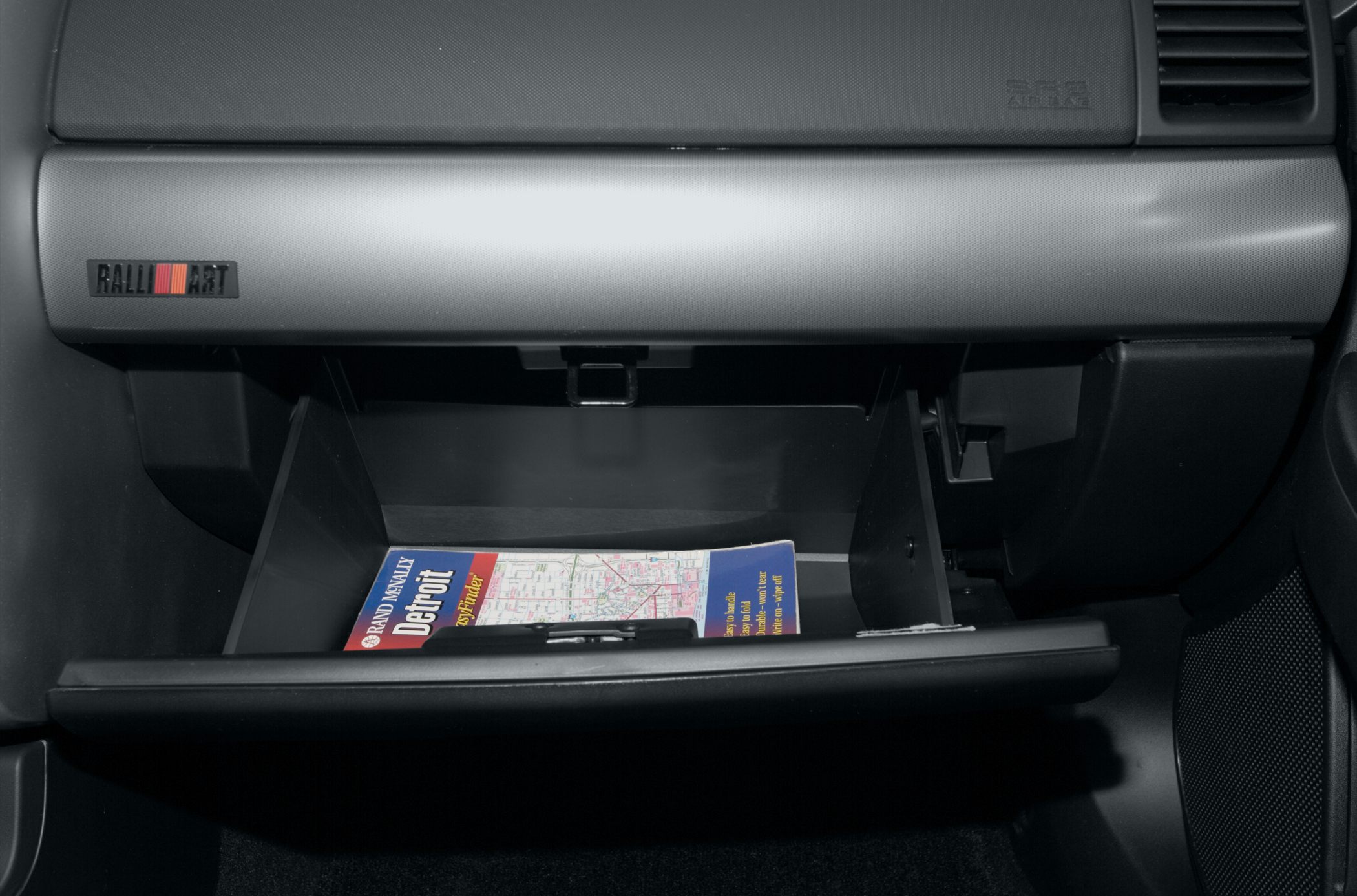 Open glove compartment and Ralliart badge on passenger side dashboard