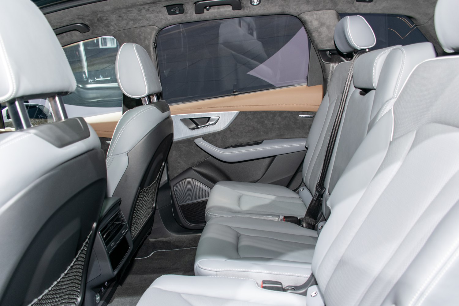 Luxury rear passenger seats with grey leather upholstery and detailed door panel.