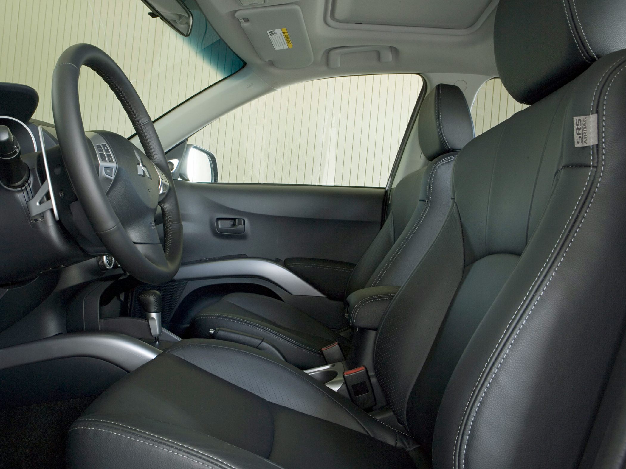 Black leather seats with contrast stitching and steering wheel with mounted controls.