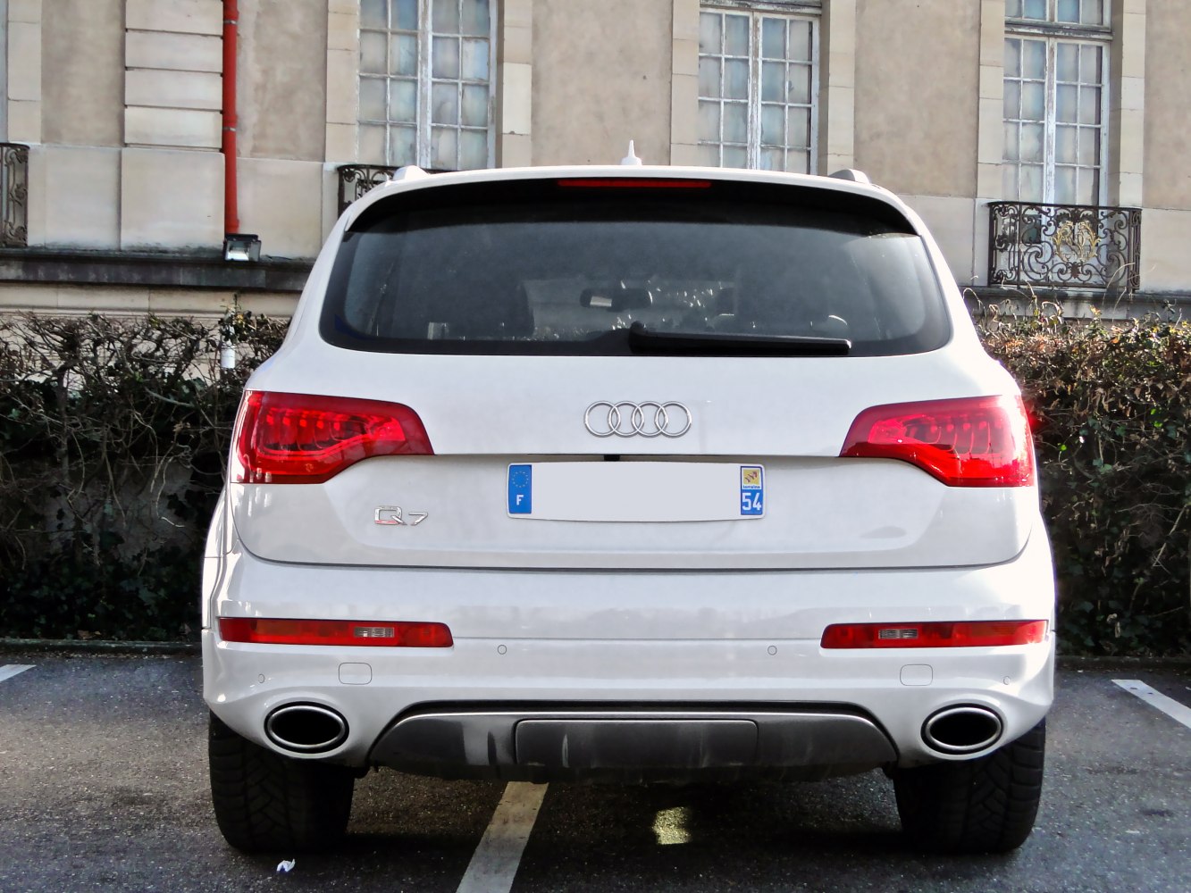 Rear view of a white SUV with distinct taillights and dual oval exhaust pipes.
