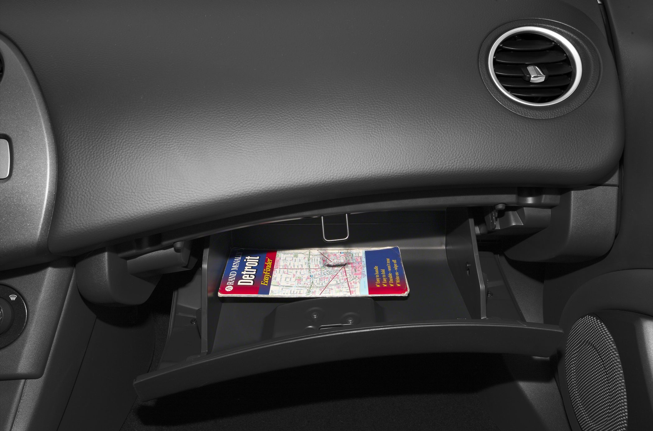 Open glove box with a map inside in car interior
