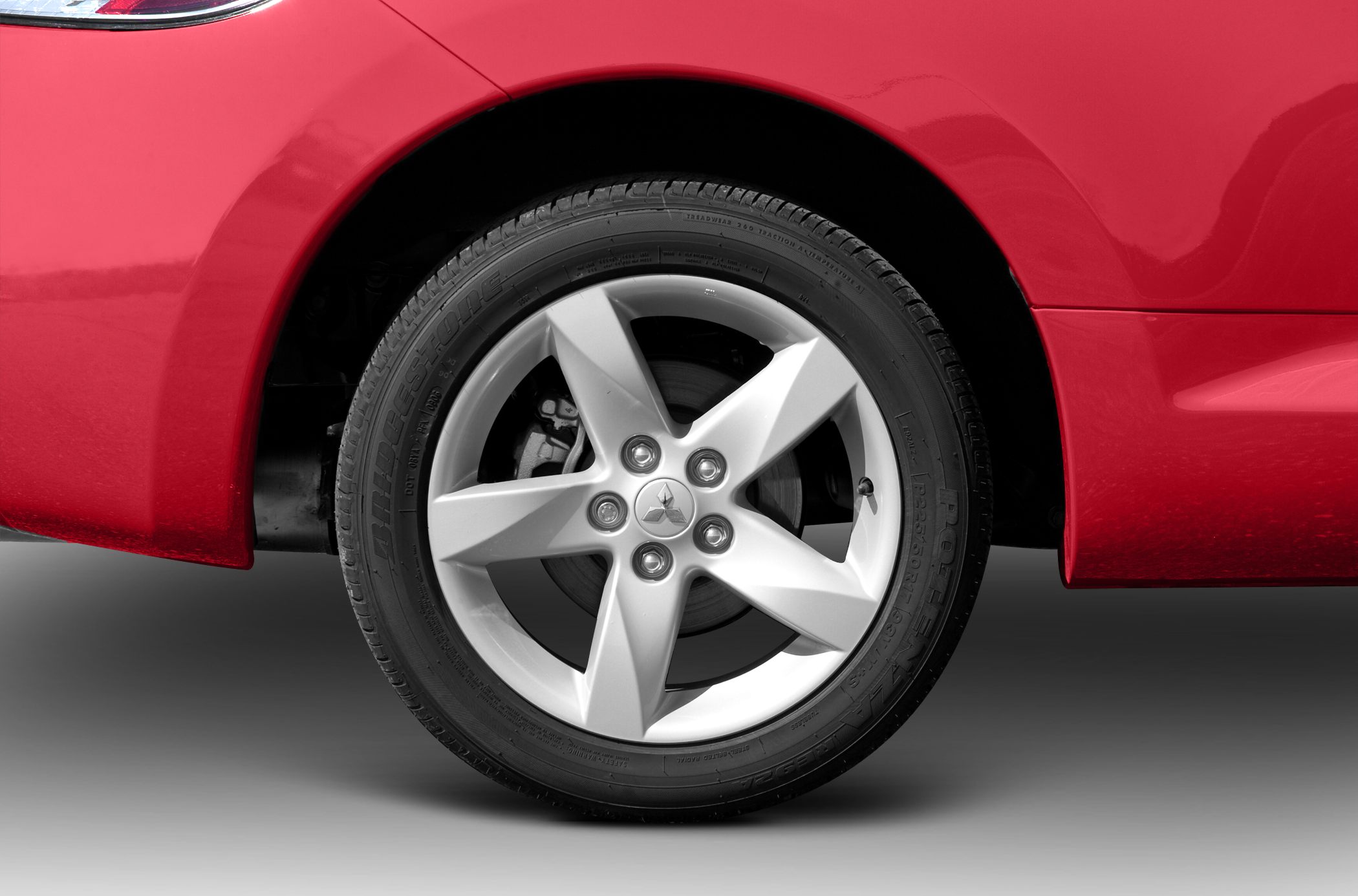 Five-spoke alloy wheel with Bridgestone tire on red car body