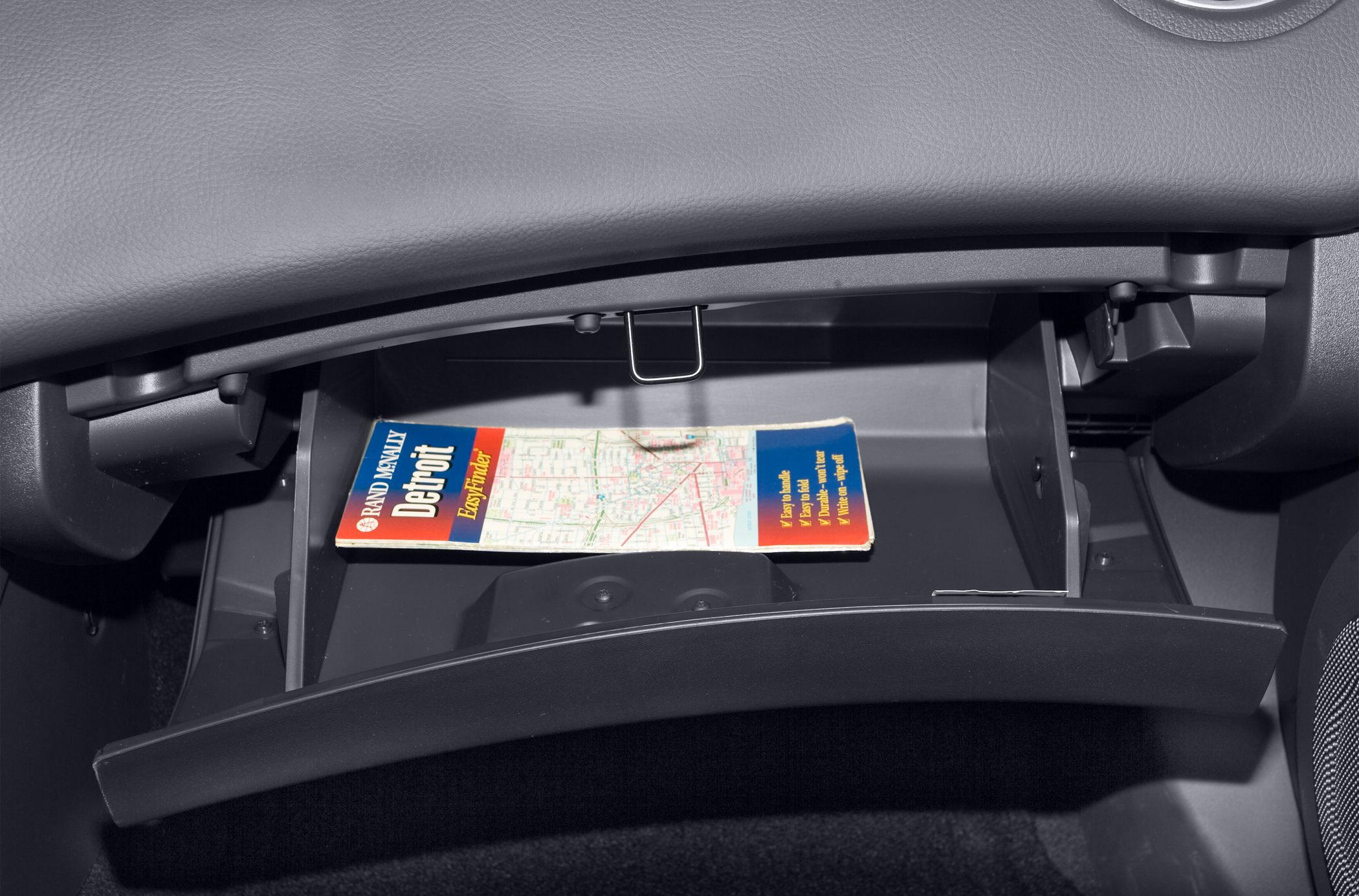 Open glove compartment with folded Detroit map inside car interior