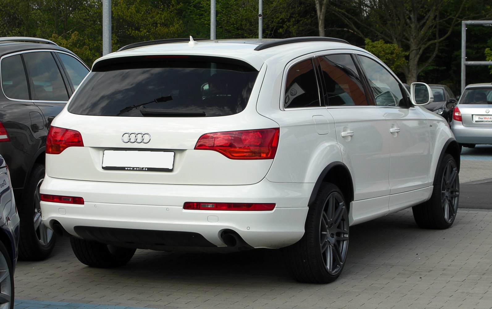 White SUV rear view with dual exhaust, taillights, and tinted windows