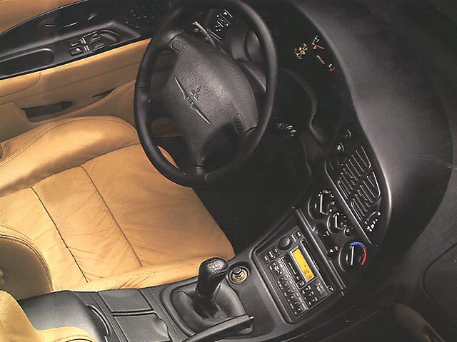 Tan leather seats, manual gearshift, and dashboard controls in a sports coupe interior
