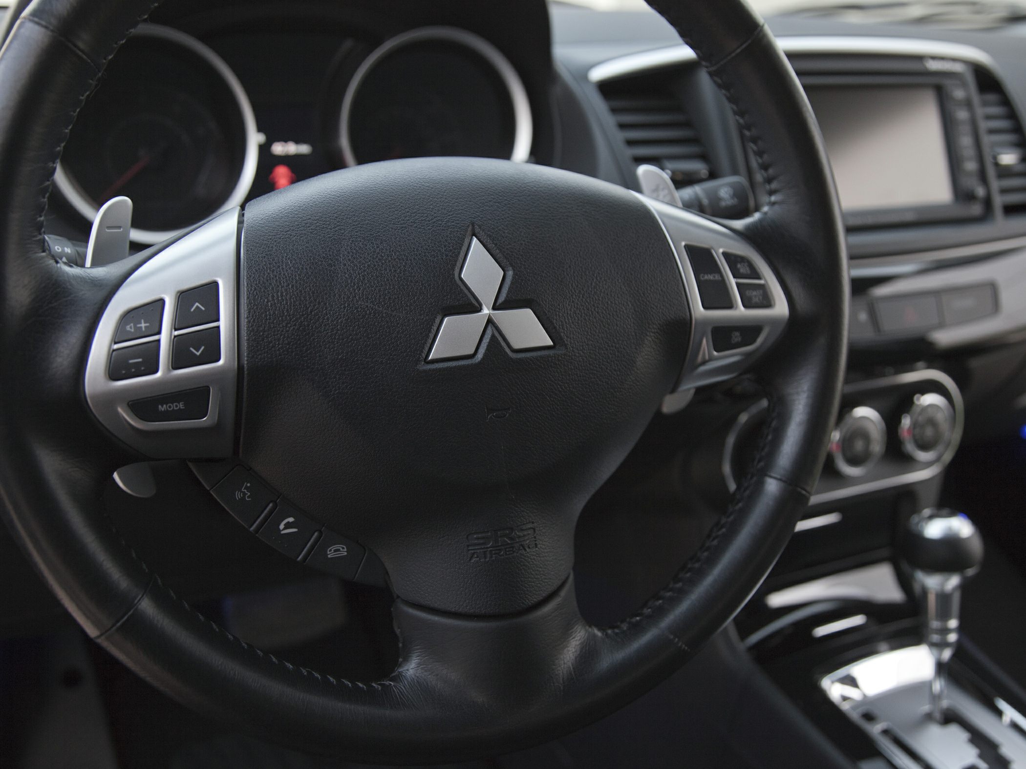 Black leather steering wheel with control buttons and gear shift knob