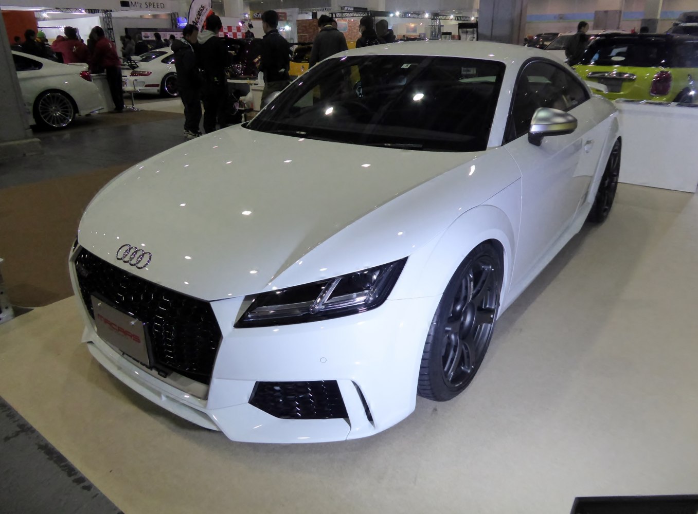 White coupe front view with black grille and multi-spoke wheels