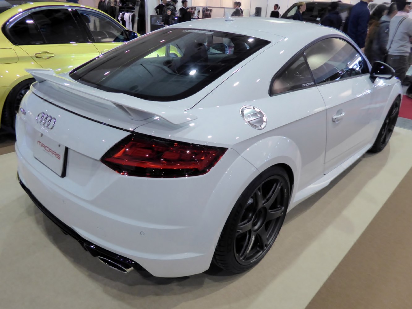 Rear side of white sports coupe with prominent spoiler and sleek LED tail lights