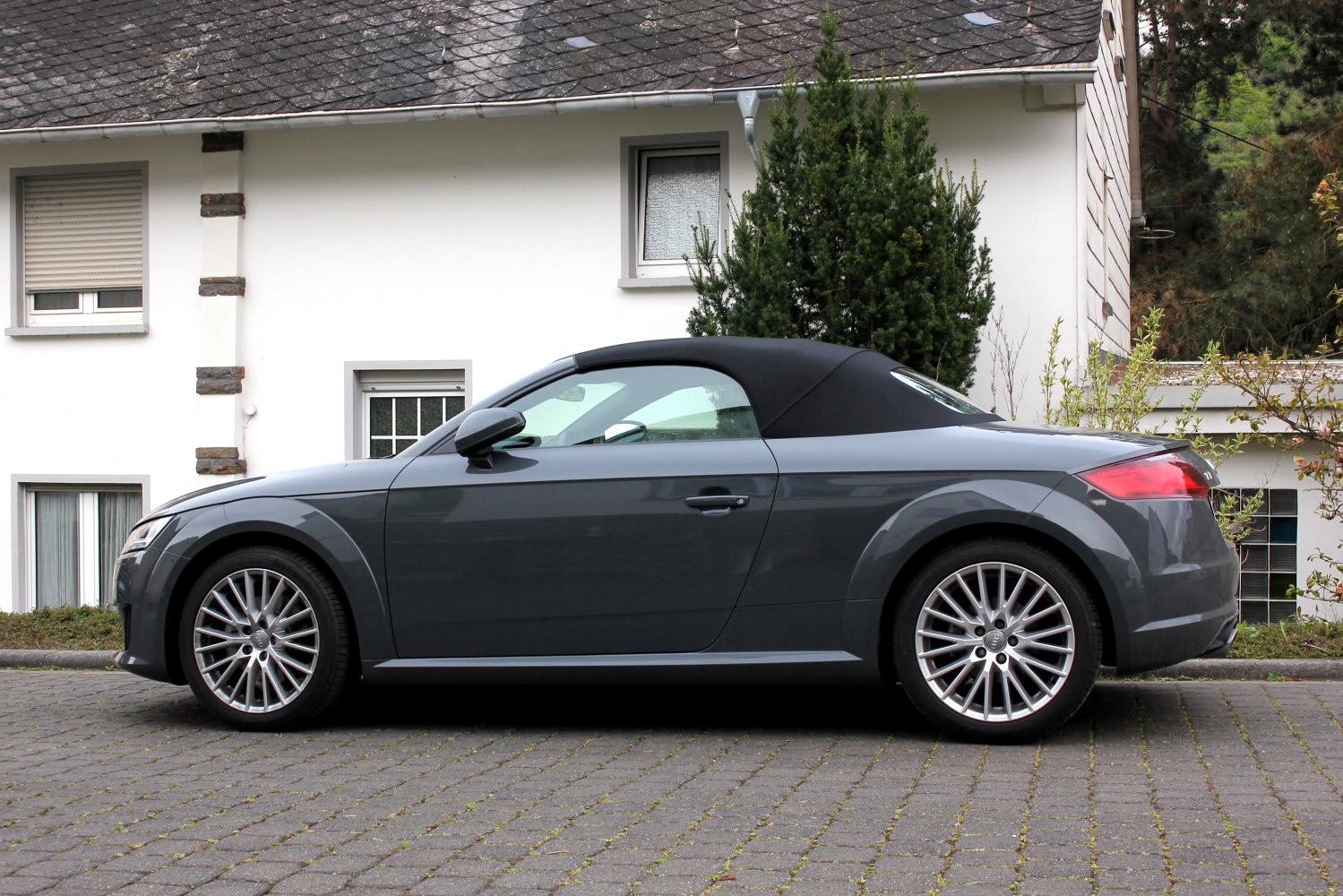 Side profile of a convertible sports coupe with soft top roof and alloy wheels