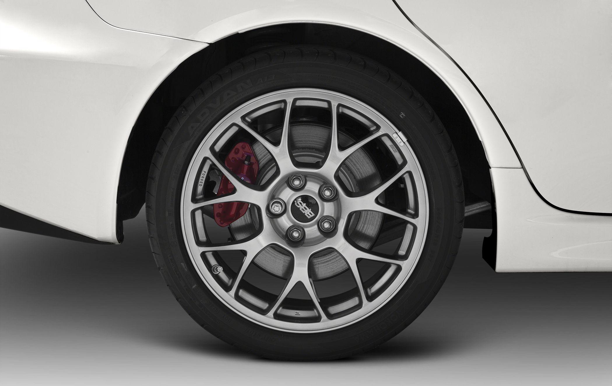 Forged multi-spoke alloy wheel with red brake caliper and performance tire.