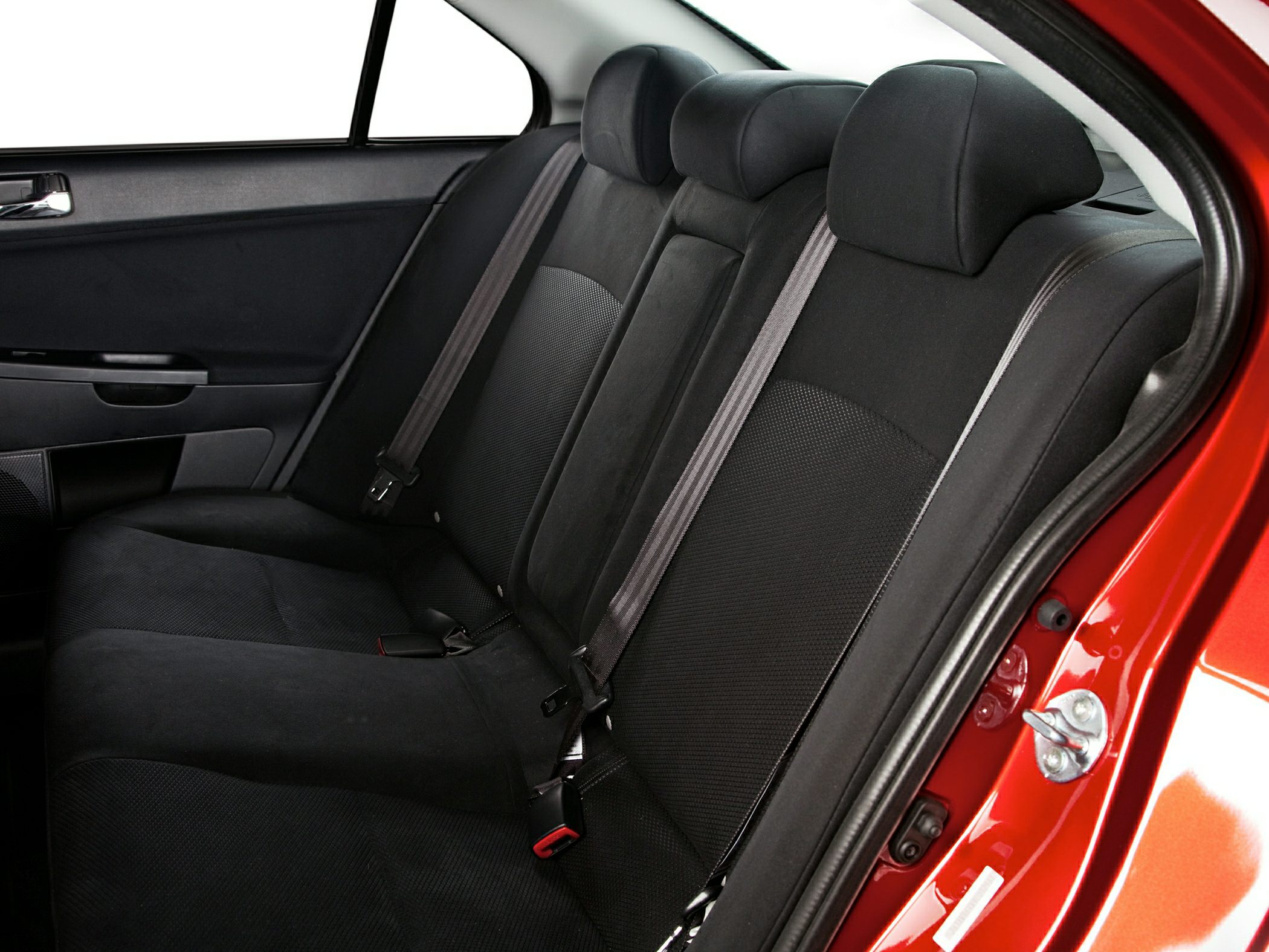 Black fabric rear seats with headrests and seat belts inside a sedan.