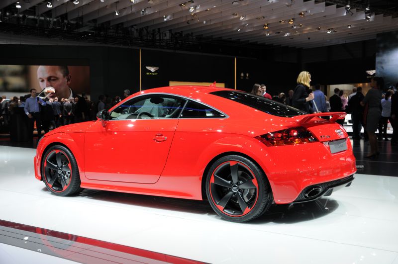 Red sports coupe with rear spoiler, black and red rims, and dual exhaust.