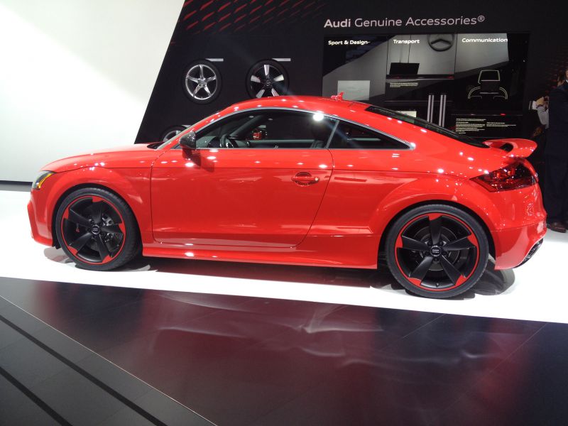 Red coupe side profile with black and red sport wheels.