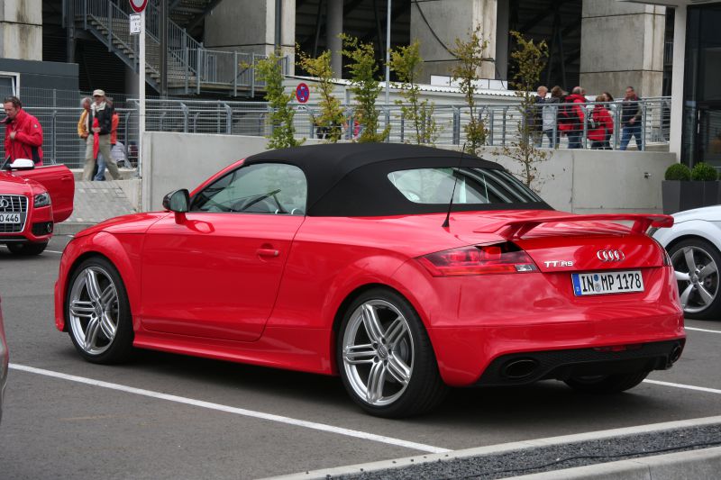 Red convertible with rear spoiler and alloy wheels, side-rear view