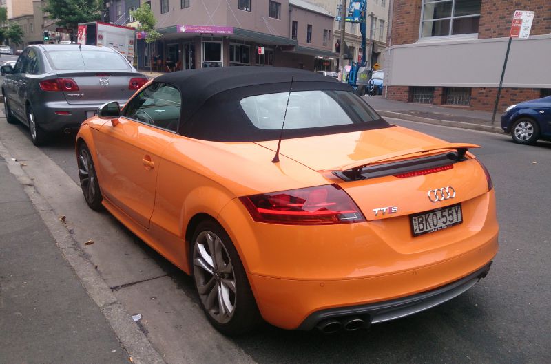 Rear view of orange convertible with rear spoiler and dual exhaust