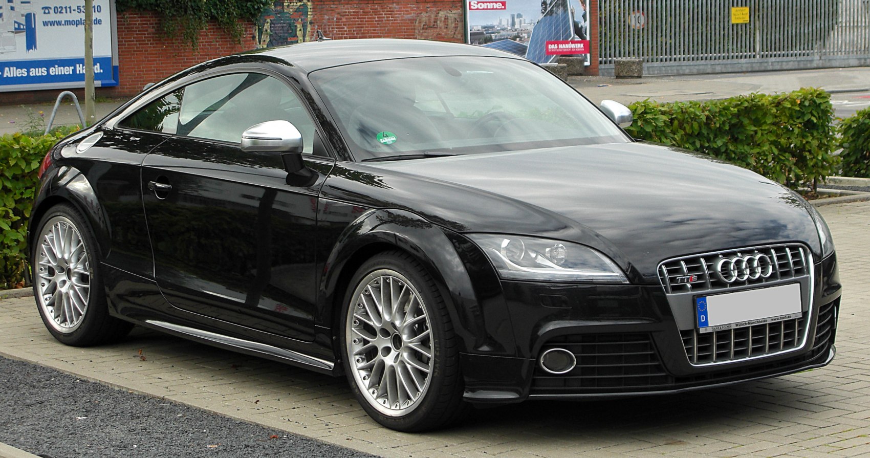 Front side view of a sleek coupe with alloy wheels and distinctive headlights