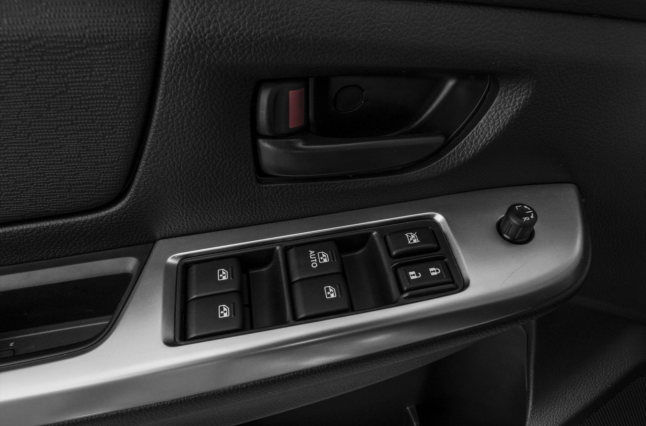 Power window and mirror controls on textured door panel.
