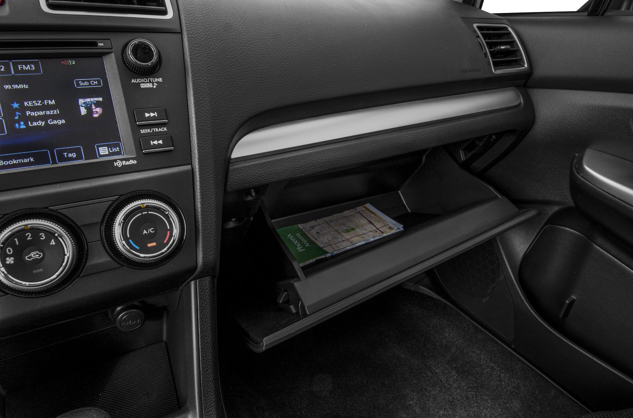 Dashboard with audio system and open glovebox holding a map