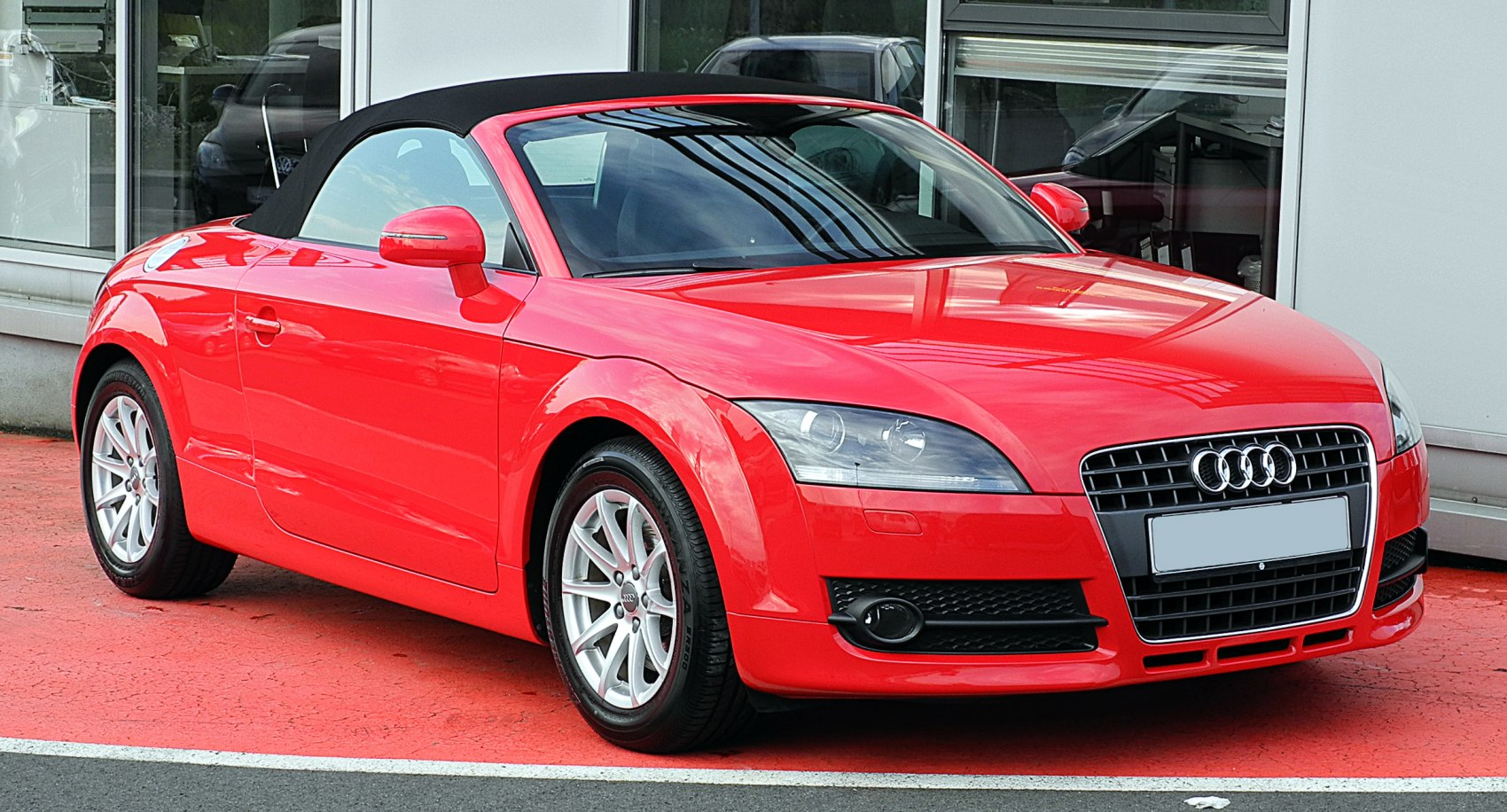 Red convertible with black soft top and sporty front design