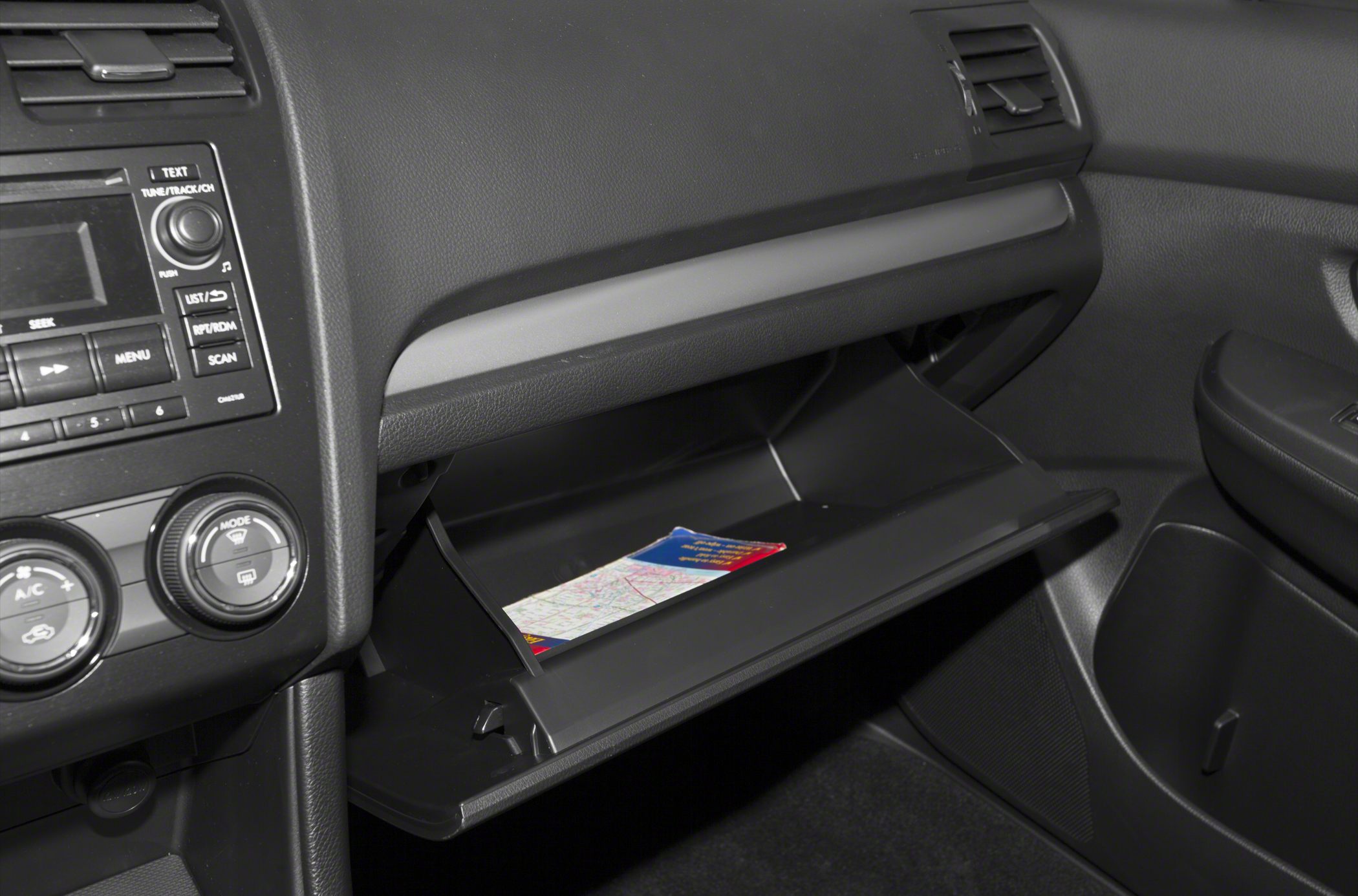 Open glove compartment and dashboard controls with climate and audio knobs