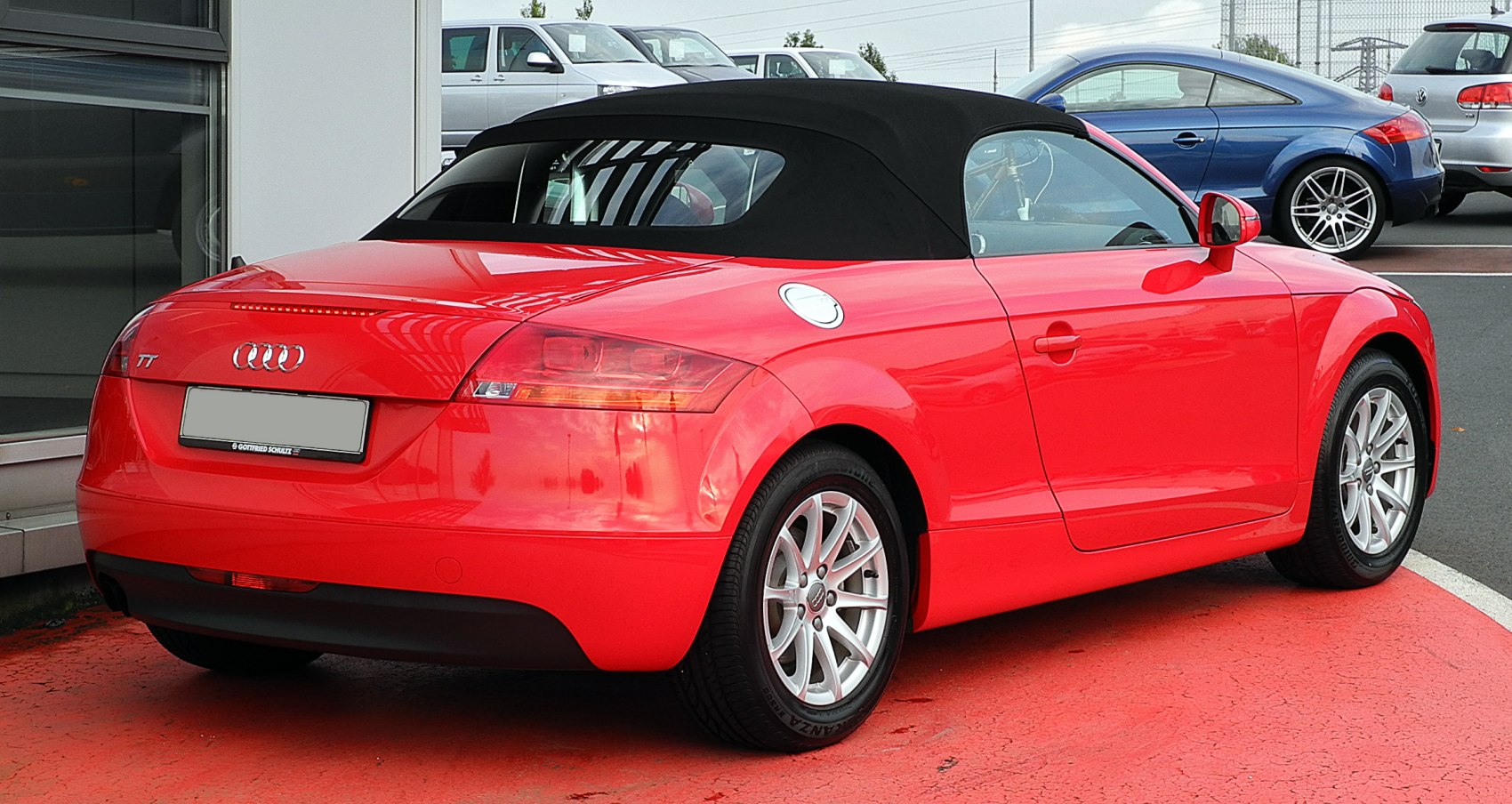 Red convertible with black soft top showing rear and side details