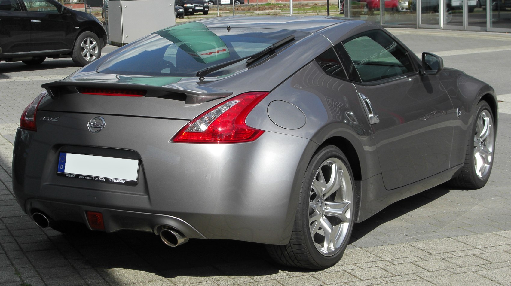 Rear spoiler and dual exhaust pipes on sports coupe rear.