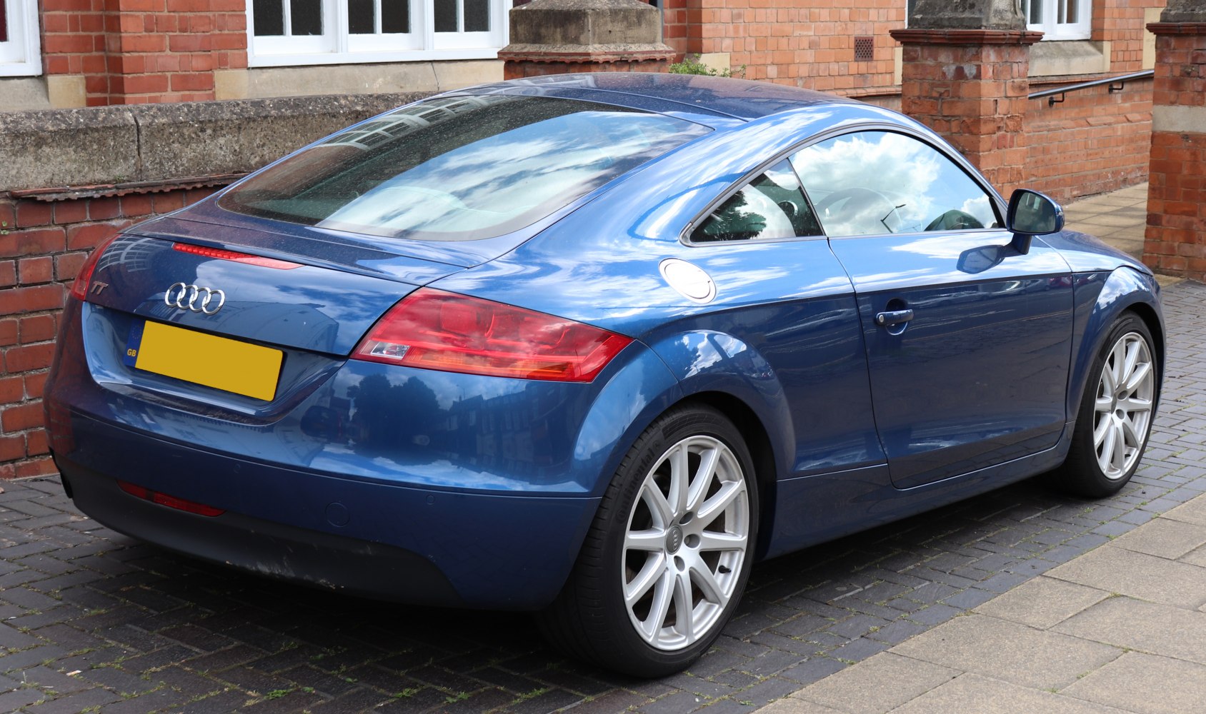 Rear and side view of a blue coupe with alloy wheels and distinctive taillights