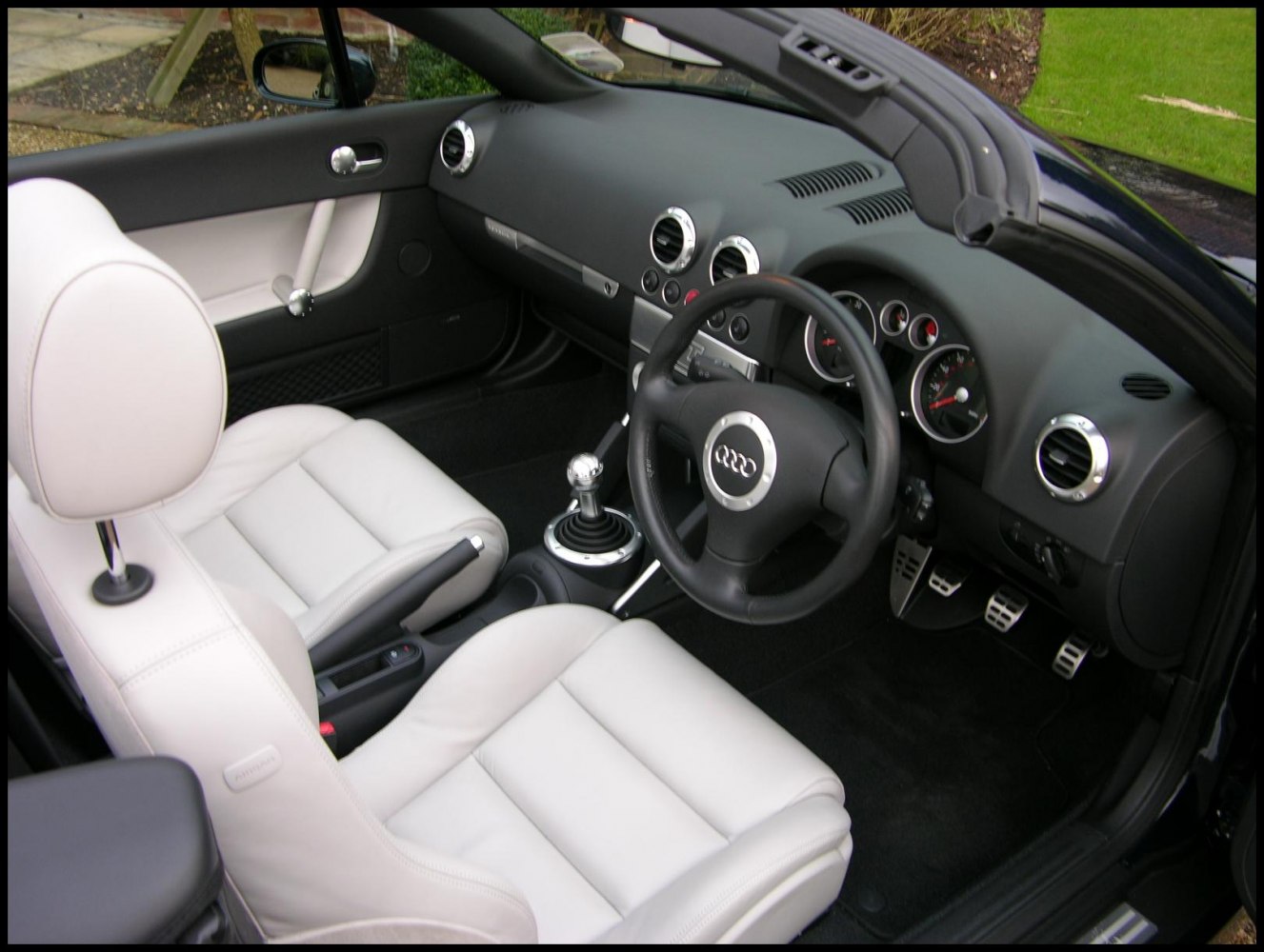 White leather seats with manual gearbox and circular air vents in compact sports interior